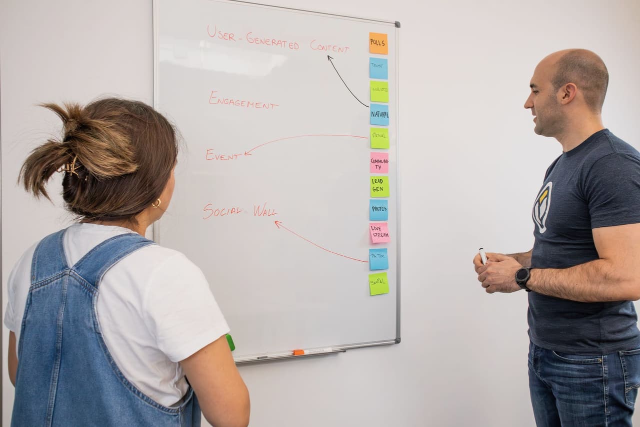 Two colleagues discussing a plan in front of a whiteboard in a bright office